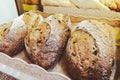 Freshly baked brown olive sour bread made from wheat flour in basket on shelf of bakery shop. Photo of delicious, healthy