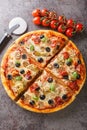 Freshly baked capricciosa pizza with artichokes, prosciutto ham, olives, mushrooms and cheese close-up on a wooden board. Vertical Royalty Free Stock Photo