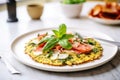 freshly baked cauliflower pizza with basil leaves on a white plate