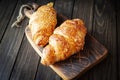 Freshly baked golden croissants on dark wooden cutting board Royalty Free Stock Photo