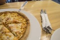 Freshly baked cheese pizza, appetizing cut into pieces lies on a white plate, top view of the table and Cutlery Royalty Free Stock Photo