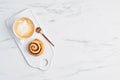 Freshly baked cinnamon roll and coffee with latte art