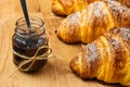 Freshly baked croissant with a berry jam in a jar on a wooden desk. French breakfast concept. Homemade pastry. Royalty Free Stock Photo