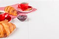 Freshly baked croissant on napkin, cup of coffee in red cup on white wooden background. French breakfast. Fresh pastries for break Royalty Free Stock Photo