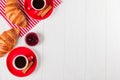 Freshly baked croissant on napkin, cup of coffee in red cup on white wooden background. French breakfast. Fresh pastries for break Royalty Free Stock Photo