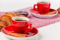 Freshly baked croissant on napkin, cup of coffee in red cup on white wooden background. French breakfast. Fresh pastries for break Royalty Free Stock Photo