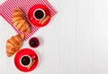 Freshly baked croissant on napkin, cup of coffee in red cup on white wooden background. French breakfast. Fresh pastries for break Royalty Free Stock Photo