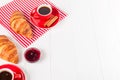 Freshly baked croissant on napkin, cup of coffee in red cup on white wooden background. French breakfast. Fresh pastries for break Royalty Free Stock Photo