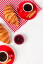 Freshly baked croissant on napkin, cup of coffee in red cup on white wooden background. French breakfast. Fresh pastries for break Royalty Free Stock Photo