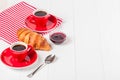 Freshly baked croissant on napkin, cup of coffee in red cup on white wooden background. French breakfast. Fresh pastries for break Royalty Free Stock Photo
