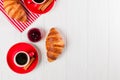 Freshly baked croissant on napkin, cup of coffee in red cup on white wooden background. French breakfast. Fresh pastries for break Royalty Free Stock Photo