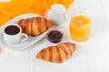 Freshly baked croissant orange juice, jam, cup of black coffee on white wooden background. French breakfast. Fresh pastries for mo Royalty Free Stock Photo