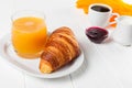 Freshly baked croissant orange juice, jam, cup of black coffee on white wooden background. French breakfast. Fresh pastries for mo