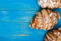 Freshly baked croissants with almond flakes, on a blue wooden background.