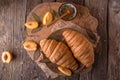 Freshly baked croissants with fruit jam, caramel and honey on wooden boards. Royalty Free Stock Photo