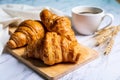 Freshly baked croissants on wooden cutting board with coffee Royalty Free Stock Photo