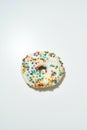 Freshly baked delicious donut with colorful sprinkles and sugar or chocolate glaze isolated on white background vertical Royalty Free Stock Photo