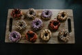 Freshly baked donuts, with chocolate and vanilla, differently decorated, served on a cutting board