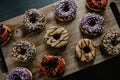 Freshly baked donuts, with chocolate and vanilla, differently decorated, served on a cutting board