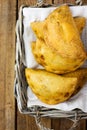 Freshly baked Empanadas Turnover Pies with vegetable cheese filling in tomato sauce in wicker basket. Plank wood background.