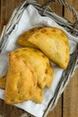 Freshly baked Empanadas Turnover Pies with vegetable cheese filling in tomato sauce in wicker basket. Wood background. Royalty Free Stock Photo