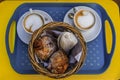 Freshly baked French almond croissants and cappuccino on a platter at breakfast at a cafe in Nice, France flat lay view