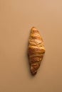 Freshly baked French buttery flaky croissant on brown tabletop background. Breakfast energy concept