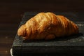 Freshly baked French croissants on a black plate with a fork and knife on a gray concrete background. View from above. Royalty Free Stock Photo