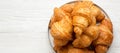 Freshly baked golden croissants on grey round plate on a white wooden background, overhead view. From above, top view, flat lay. Royalty Free Stock Photo