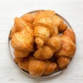 Freshly baked golden croissants on grey round plate on white wooden background, top view. From above, overhead, flat lay Royalty Free Stock Photo