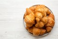 Freshly baked golden croissants on grey round plate on white wooden table, top view. From above, overhead, flat lay. Royalty Free Stock Photo