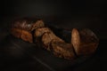 Freshly baked homemade artisan sourdough bread on wooden boards over dark background