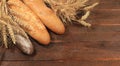 Freshly baked homemade bread, french sourdough baguette with crispy crust and ears of rye and wheat on wooden background with Royalty Free Stock Photo