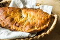 Freshly baked homemade calzone with sweet apple pie filling, golden crust, in wicker basket on linen napkin