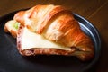 Freshly baked homemade delicious croissant sandwich ham cheese in black plate on wooden breakfast table Royalty Free Stock Photo