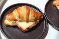 Freshly baked homemade delicious croissant sandwich ham cheese in black plate on wooden breakfast table, top view of breakfast Royalty Free Stock Photo