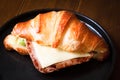 Freshly baked homemade delicious croissant sandwich ham cheese in black plate on wooden breakfast table, top view of breakfast Royalty Free Stock Photo