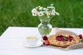 Freshly baked homemade galette or open strawberry pie, a cup of herbal tea and a vase with a bouquet of daisy flowers. Soft Royalty Free Stock Photo