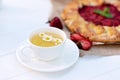 Freshly baked homemade galette or open strawberry pie and fresh mint leaves with a cup of chamomile herbal tea, summer food. Soft Royalty Free Stock Photo