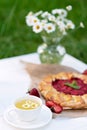 Freshly baked homemade galette or open strawberry pie and fresh mint leaves with a cup of chamomile herbal tea, summer food. Soft Royalty Free Stock Photo