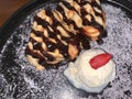 freshly baked homemade heart shaped Belgian waffles, covered with chocolate syrup and vanilla ice cream with sliced of straw berry Royalty Free Stock Photo