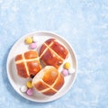 Freshly baked hot cross buns on plate with chocolate candy eggs, square, copy space Royalty Free Stock Photo