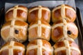 Freshly baked hot cross buns with raisins on a baking tray. Traditional English American Easter yeast pastry