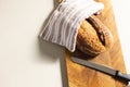 A freshly baked loaf of bread rests on a wooden cutting board beside a knife, with copy space Royalty Free Stock Photo