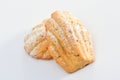 Freshly baked Madeleine cookies sprinkled with sugar powder close-up on the table, petite madeleine isolated on white backgrou