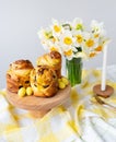 Freshly baked pastries, yellow candies, and white daffodils on a checkered cloth. A beautiful springtime table setting