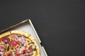 Freshly baked pizza in a cardboard box on black background, top view. Copy space. Flat lay, Royalty Free Stock Photo