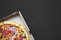 Freshly baked pizza in a cardboard box on black surface, top view. Copy space. Royalty Free Stock Photo