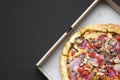 Freshly baked pizza in a cardboard box on black table, top view. Copy space. Flat lay, overhead Royalty Free Stock Photo