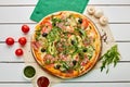 Freshly baked pizza with ham, rukkola, sauce pesto and olives served on wooden background with tomatoes, sauces and herbs. Food Royalty Free Stock Photo